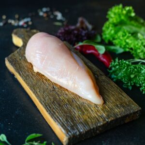 Poitrine de poulet crue avec verdures sur planche à découper